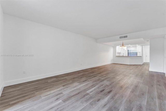 unfurnished living room featuring baseboards, visible vents, and light wood-style floors