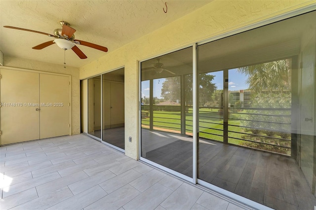unfurnished sunroom featuring a ceiling fan