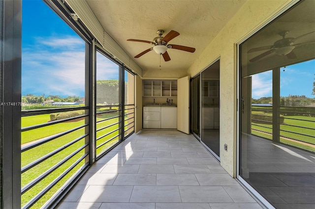 unfurnished sunroom with ceiling fan and separate washer and dryer