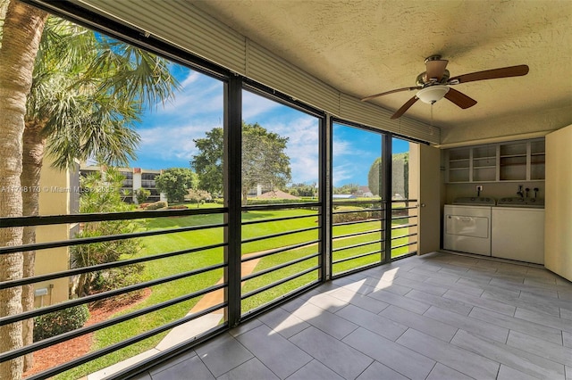 unfurnished sunroom featuring a ceiling fan and washer and dryer