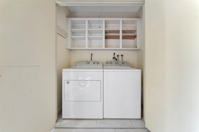 clothes washing area featuring laundry area, washing machine and clothes dryer, and light tile patterned floors