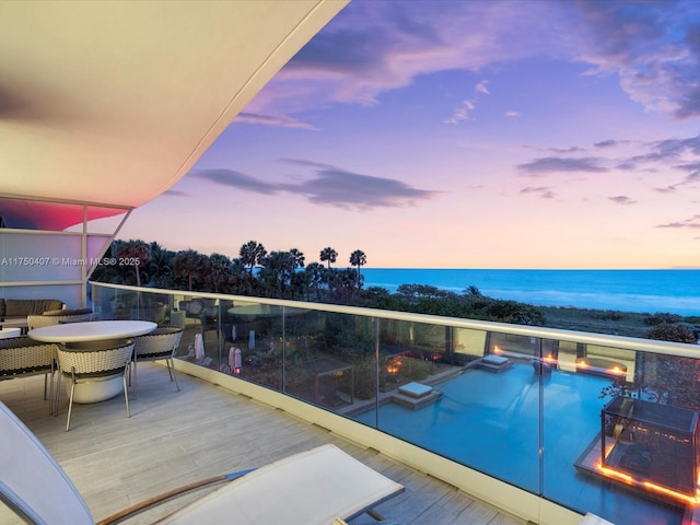 balcony with outdoor dining space and a water view