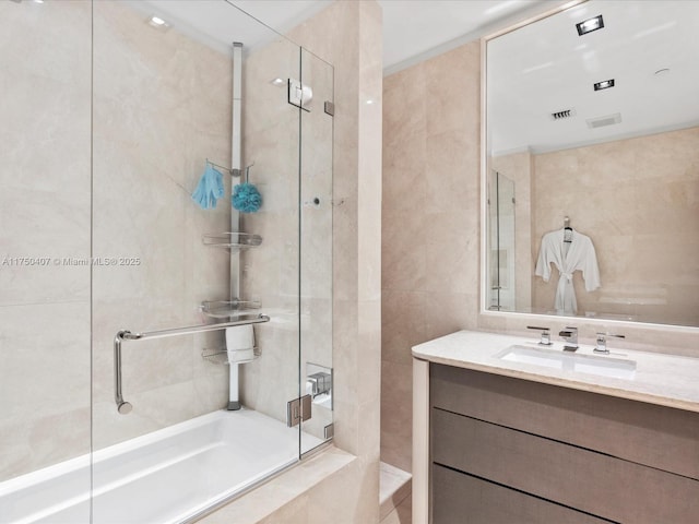 bathroom featuring a bath, a stall shower, tile walls, and vanity