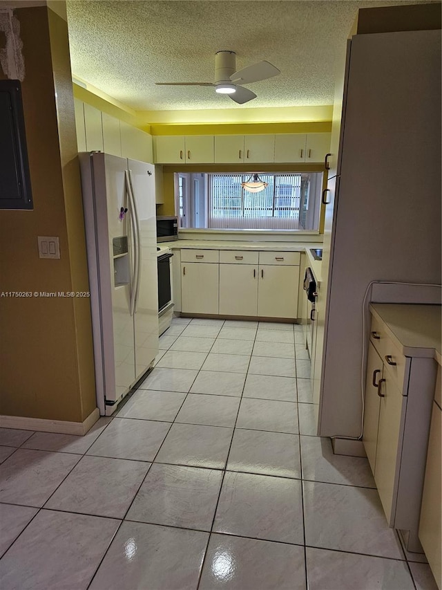 kitchen with white appliances, light tile patterned floors, ceiling fan, light countertops, and a textured ceiling