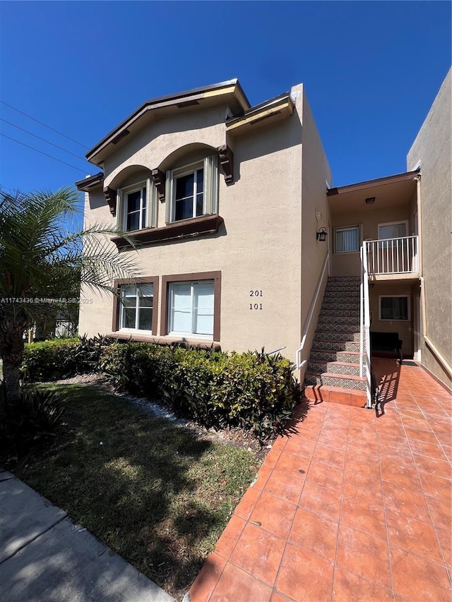 view of home's exterior with stairs and stucco siding