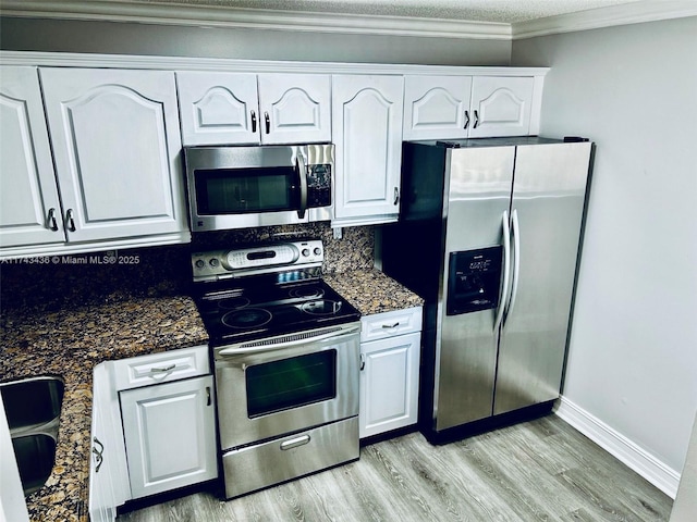 kitchen featuring crown molding, stainless steel appliances, light wood-style flooring, decorative backsplash, and white cabinetry