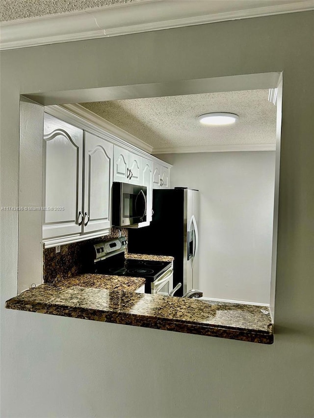 kitchen featuring a textured ceiling, appliances with stainless steel finishes, dark countertops, and crown molding