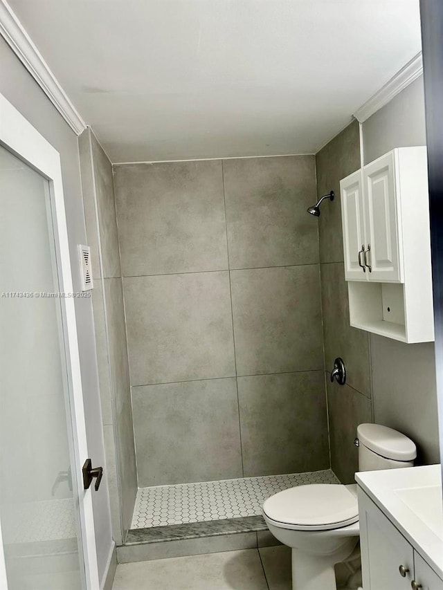 bathroom with ornamental molding, a tile shower, vanity, and toilet