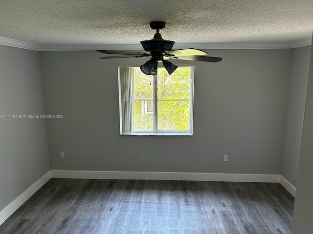 spare room with dark wood-style flooring, crown molding, and baseboards