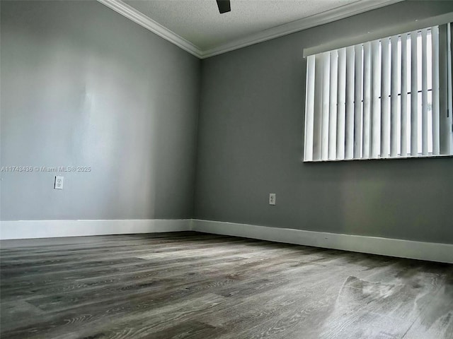 spare room with a textured ceiling, baseboards, crown molding, and wood finished floors