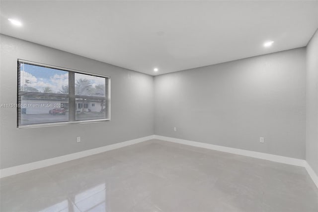 spare room with recessed lighting and baseboards