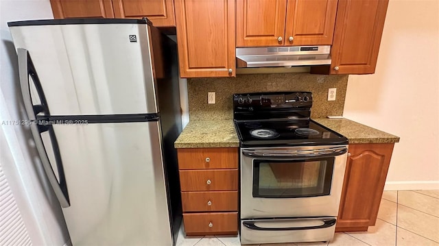 kitchen with under cabinet range hood, appliances with stainless steel finishes, light stone counters, and light tile patterned flooring