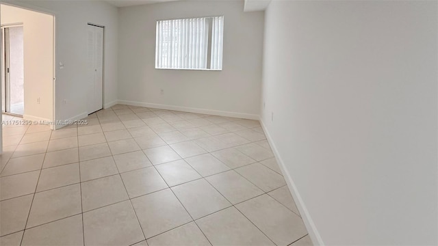 empty room featuring baseboards and light tile patterned floors