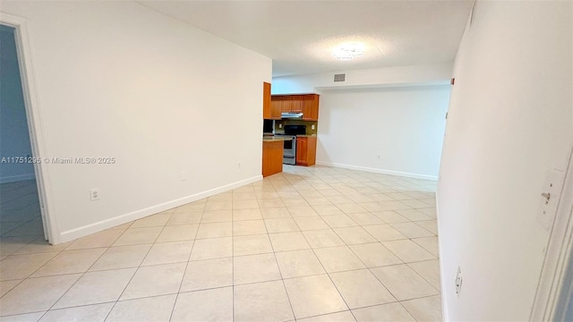 spare room with light tile patterned flooring, visible vents, baseboards, and a textured ceiling