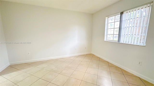 unfurnished room with light tile patterned floors and baseboards