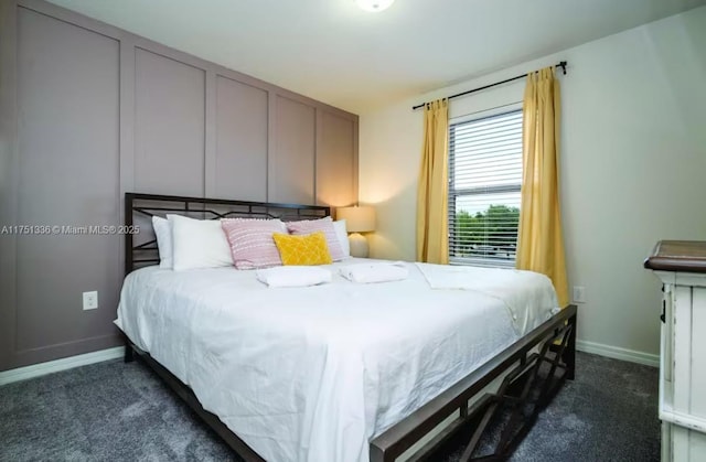 bedroom featuring dark carpet and baseboards