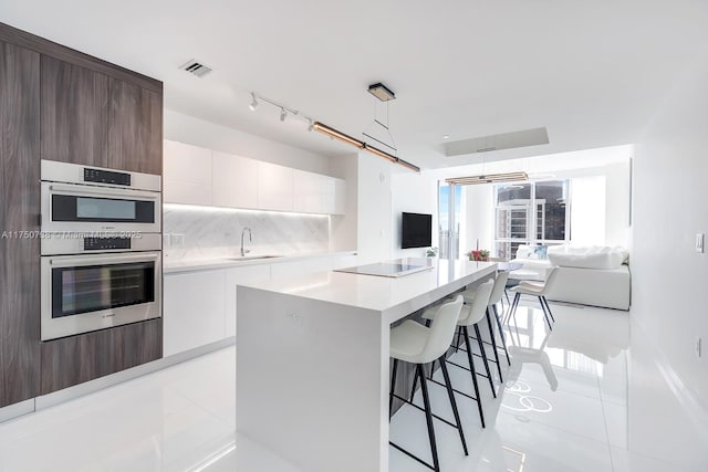 kitchen with a sink, visible vents, white cabinets, light countertops, and pendant lighting