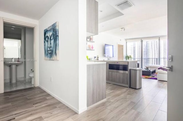 kitchen with visible vents, light wood-style flooring, open floor plan, a peninsula, and light countertops