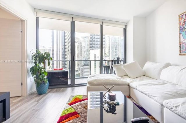 living area with a wall of windows, light wood-type flooring, and a city view