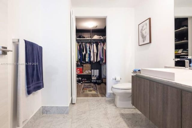 full bath featuring toilet, a walk in closet, and vanity