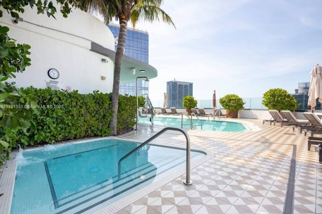 pool with a patio area, a view of city, and fence