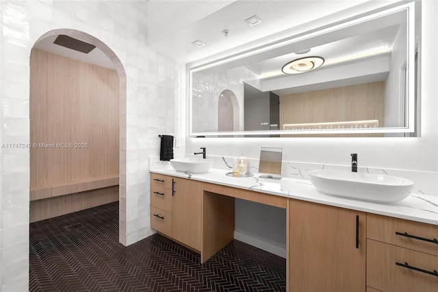 full bathroom featuring double vanity, tile walls, and a sink