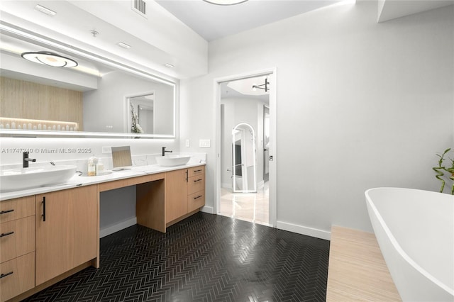 full bathroom featuring a freestanding bath, double vanity, a sink, and visible vents