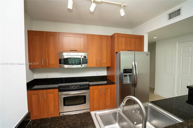 1300 Ponce De Leon Blvd Unit 709, Coral Gables, FL 33134 - kitchen featuring dark stone countertops, brown cabinets, a sink, visible vents, and stainless steel appliances