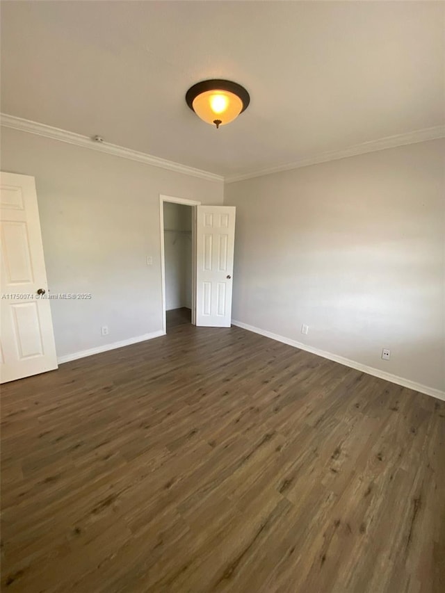 unfurnished room with ornamental molding, dark wood-style flooring, and baseboards