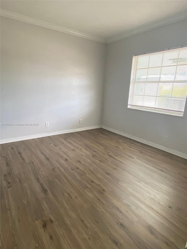 empty room featuring baseboards, dark wood finished floors, and crown molding