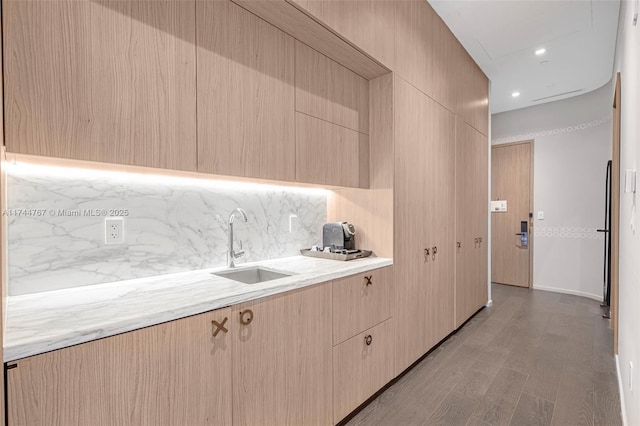 kitchen featuring modern cabinets, a sink, light countertops, light brown cabinetry, and backsplash