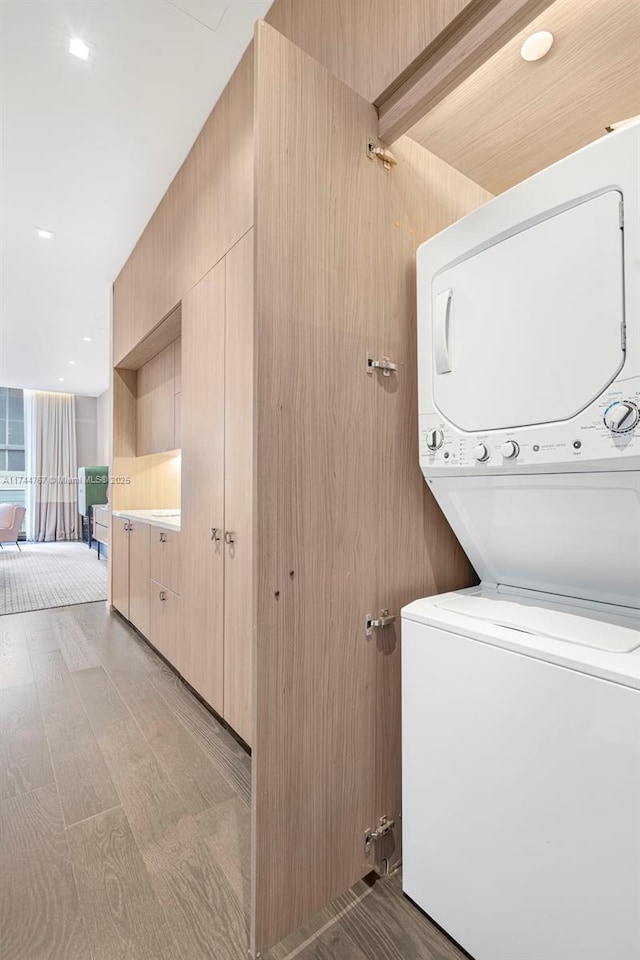 washroom with laundry area, stacked washer / dryer, and light wood-style floors