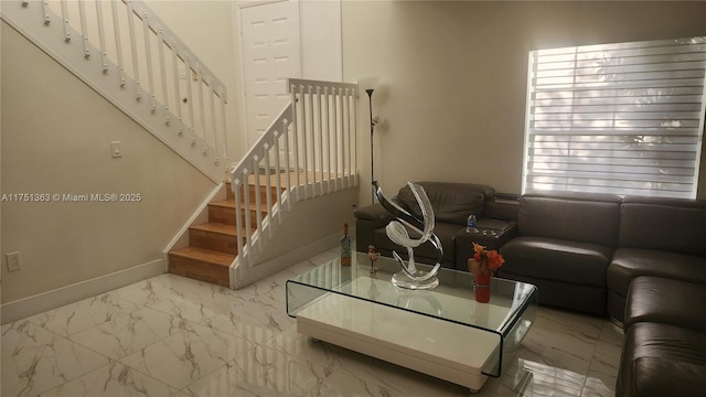 living room featuring marble finish floor, stairway, and baseboards