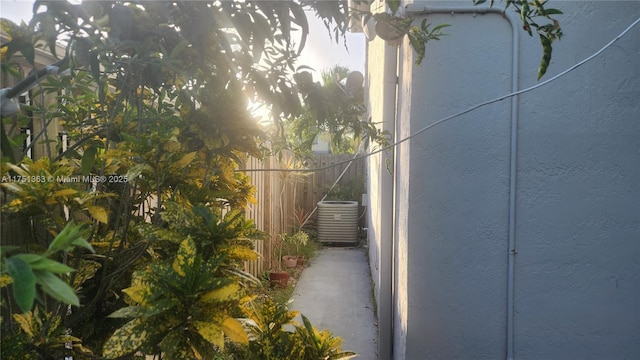 view of home's exterior featuring central AC, fence, and stucco siding