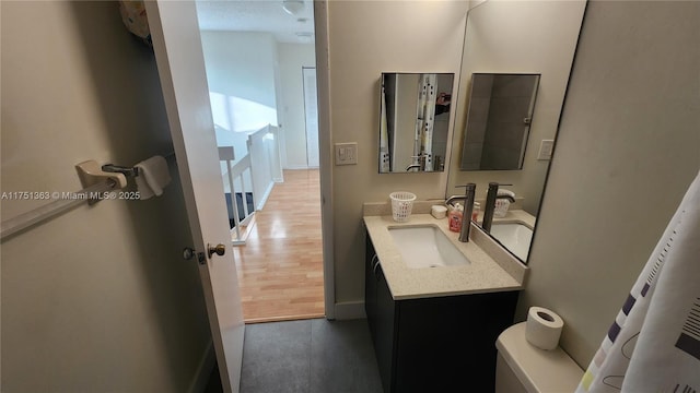 bathroom featuring toilet, baseboards, and vanity