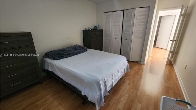 bedroom featuring light wood finished floors, baseboards, and a closet