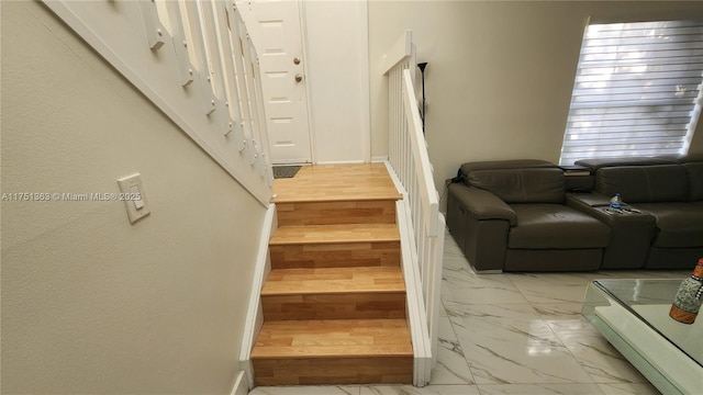 stairs featuring marble finish floor and baseboards