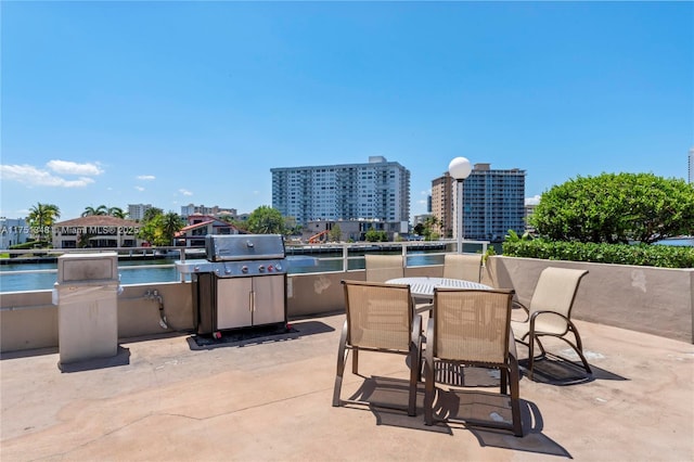 view of patio / terrace featuring a view of city, an outdoor kitchen, outdoor dining space, and a water view