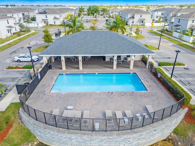 community pool with a patio area, fence, and a residential view