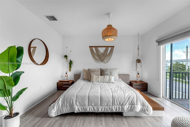 bedroom with access to outside, visible vents, baseboards, and wood finished floors