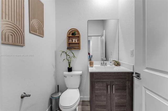 bathroom featuring baseboards, vanity, and toilet