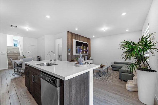 kitchen featuring dishwasher, an island with sink, open floor plan, light countertops, and a sink