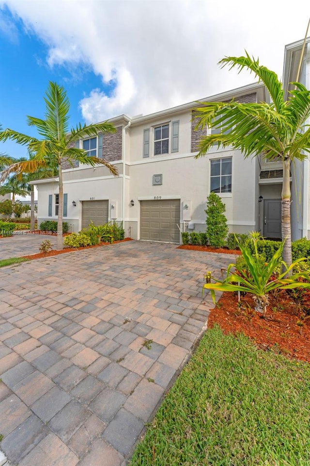 view of front facade with a garage, decorative driveway, and stucco siding