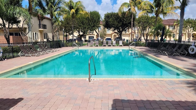 community pool with a patio area and fence