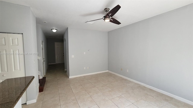 empty room featuring a ceiling fan, baseboards, and light tile patterned floors