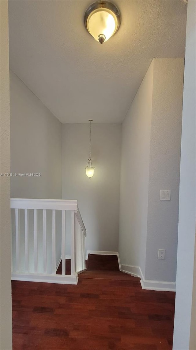 stairs featuring a textured ceiling, wood finished floors, and baseboards