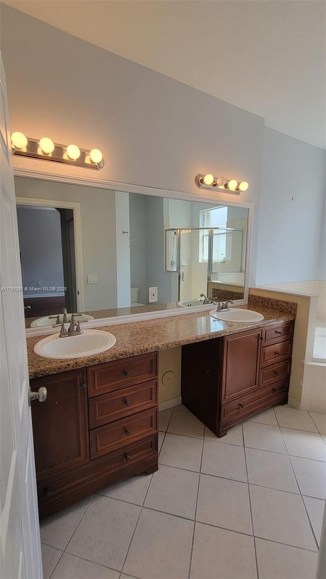 full bathroom featuring toilet, a shower stall, a sink, and tile patterned floors