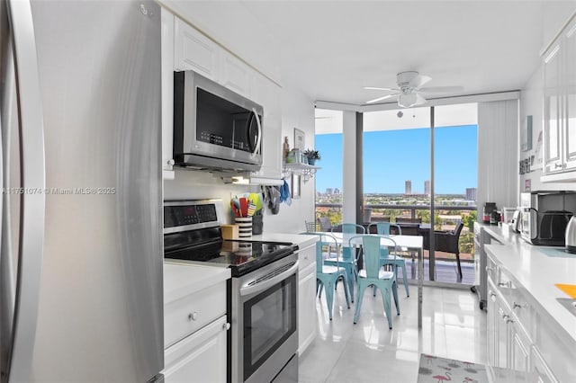 3598 Yacht Club Dr Unit 1002, Aventura, FL 33180 - kitchen with floor to ceiling windows, stainless steel appliances, white cabinets, light countertops, and ceiling fan