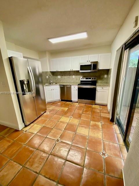 kitchen featuring white cabinets, tasteful backsplash, stainless steel appliances, and light countertops