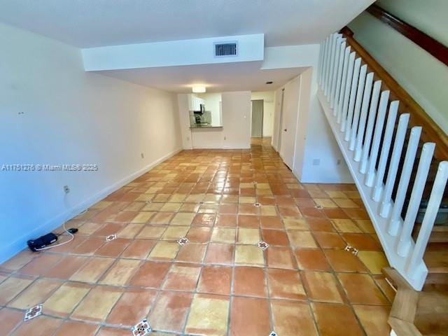 interior space featuring light tile patterned floors, visible vents, baseboards, and stairs